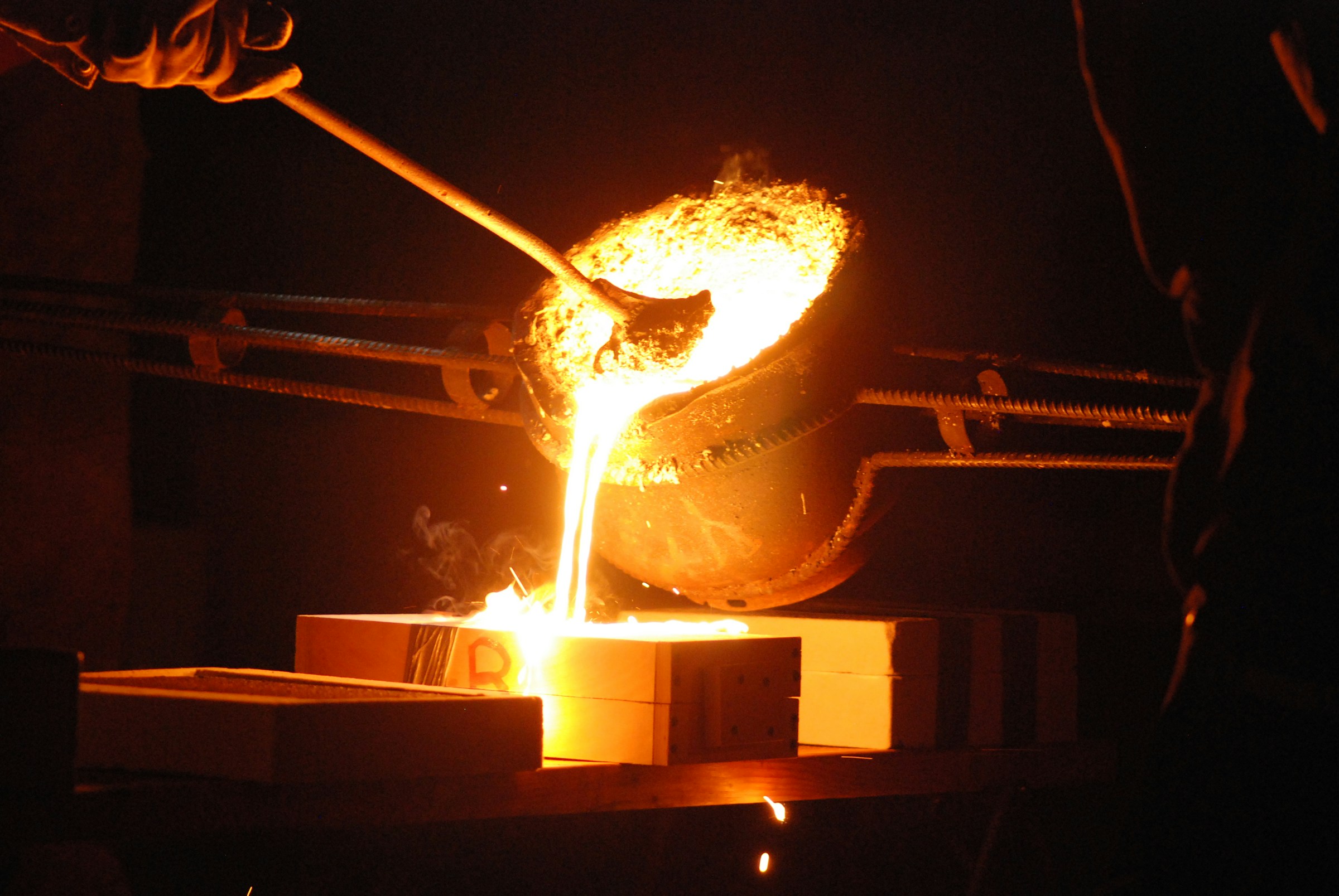 Industrial high-temperature gold smelting and pouring molten gold into ingot molds in secure DRC laboratory